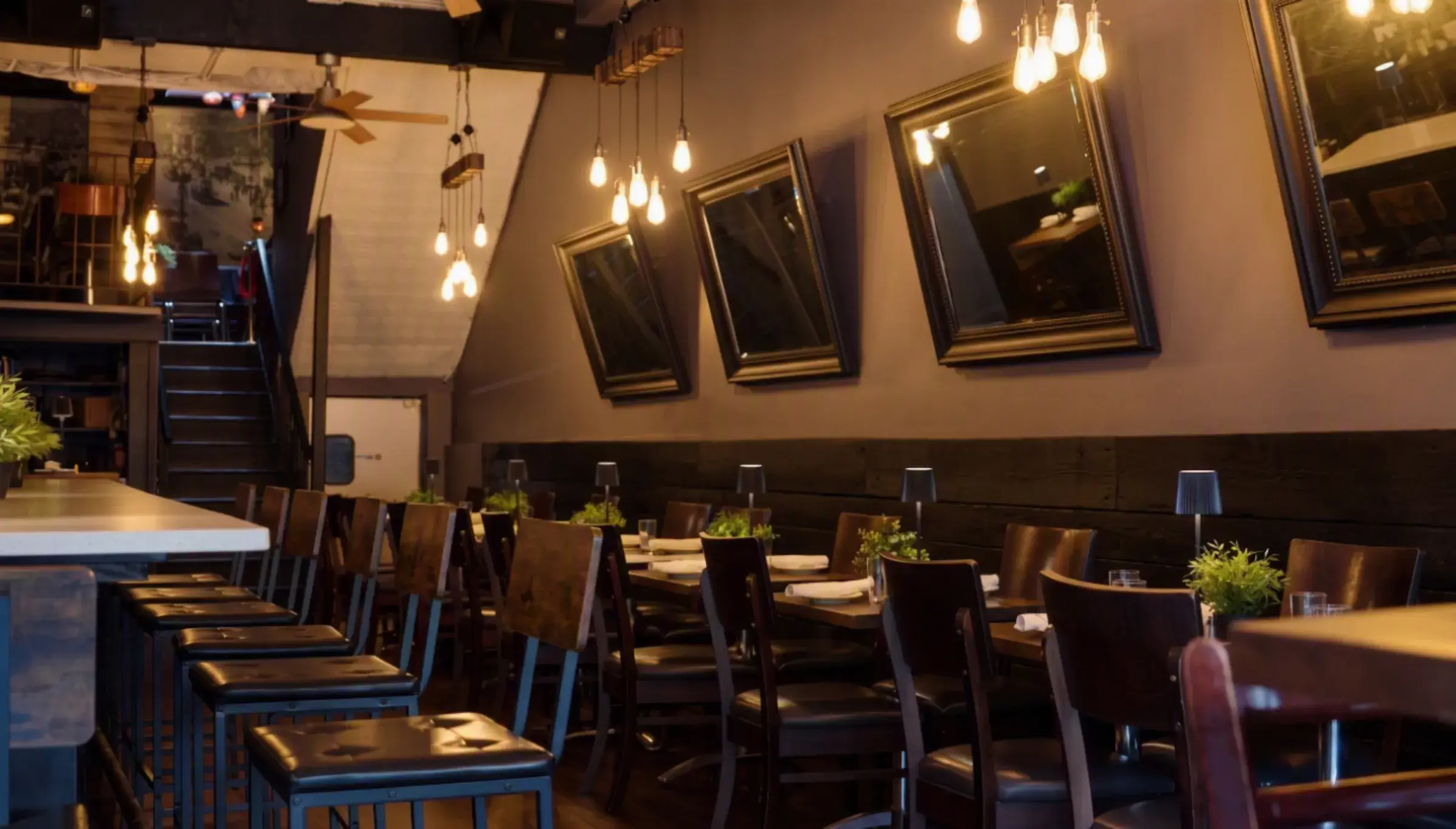 Mezè DC's candlelit dining room with warm Edison lights and the staircase to the upstairs room